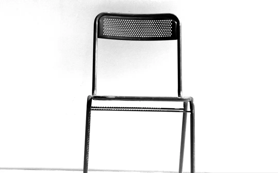 Black and white photo of an empty chair in a light studio